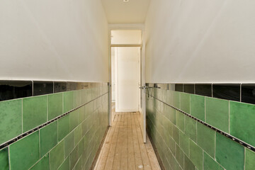 a long hallway with green tiles on the walls and wood flooring in an apartment building, taken from above