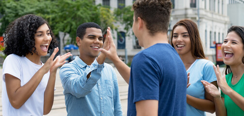 Happy multiethnic team of young adults give high five to friend