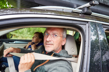 Elderly man wearing seat belt while traveling in car