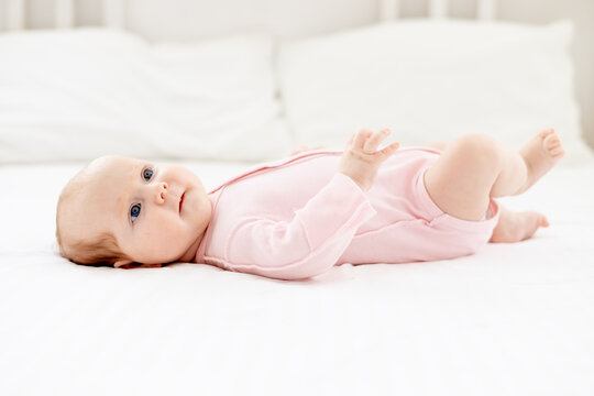 little newborn baby girl lies on a white cotton bed at home