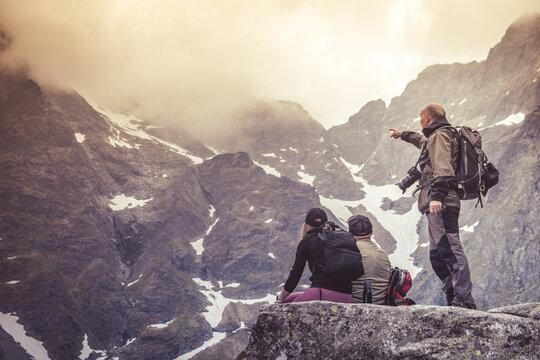 A mountain guide telling a young couple about the mountains. Mountain trekking theme.