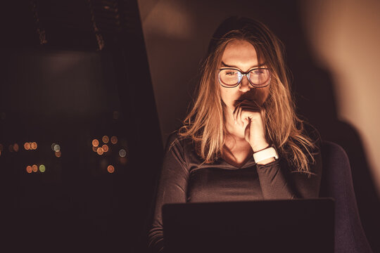 Reading news on laptop at night. Warm colors.