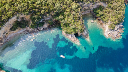 Aerial top down view of a swimming tourists and speedboat anchored in the turquoise sea