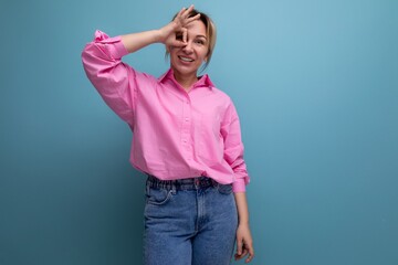 young smiling european blond office worker woman dressed in a pink shirt and jeans