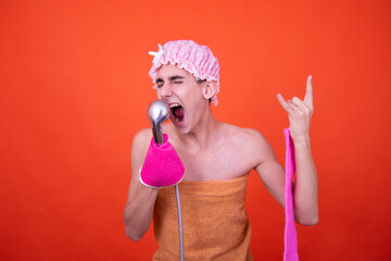 A funny guy with a pink shower cap bathes and sings songs. Orange background.