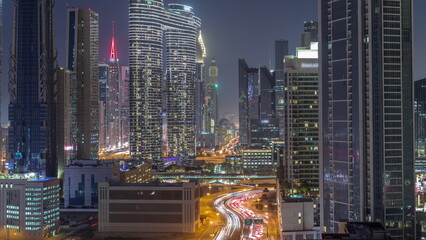 Many towers and skyscrapers with traffic on streets in Dubai Downtown and financial district night timelapse.