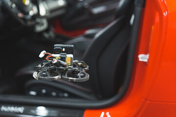 FPV drone flying near a red car in the workshop. High quality photo
