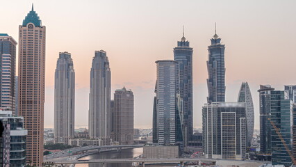 Cityscape with skyscrapers of Dubai Business Bay and water canal aerial day to night timelapse.
