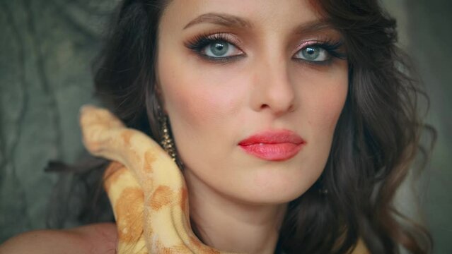 fantasy woman queen of snakes. Girl vampire fashion model posing with yellow tiger python snake animal. Beauty face. Lady love pet anaconda crawls over neck body face. black sexy dress. 4k art footage
