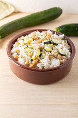 Basmati rice salad bowl with chickpeas and zucchini, served on a wooden background. Complete vegan dish quick to cook.