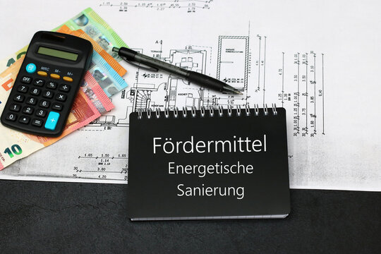 Bauplan mit Geld und Notizblock, Zusch&uuml;sse f&uuml;r die energetische Sanierung einer Immobilie.	