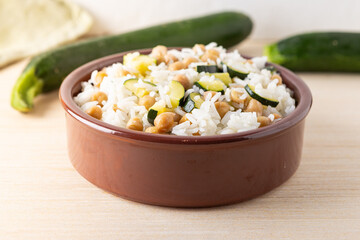 Basmati rice salad bowl with chickpeas and zucchini, served on a wooden background. Complete vegan dish quick to cook.