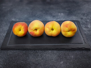 Harvest of peaches for food or juice. fresh organic fruit, vegan food. Large peaches on dark table background, selective focus.