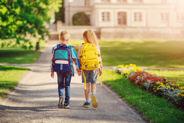 Girl and boy going to the school holding hands to study at it.