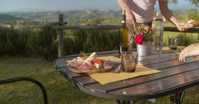two people setting table in a garden with view of mountains