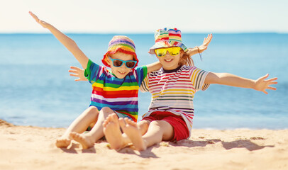 Boy and girl sitting on the sand near the sea.