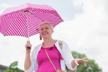 middle-aged woman with a short haircut with an umbrella protecting from sun