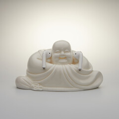 Buddha statue in wireless headphones on a white background