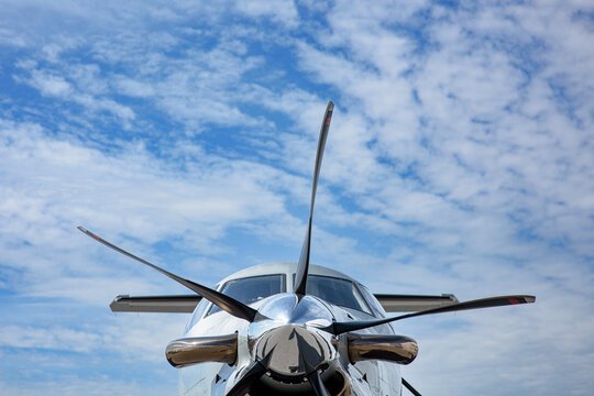 The nose of a Pilatus as seen from the front looking up.  Blue sky and cirrus clouds in the background. 