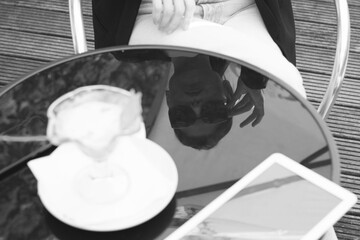 reflection on the table of a business woman in sunglasses eats melted ice cream