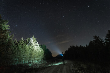 Night scene, a man with a headlamp in the forest under the starry sky in autumn. © Dmitri