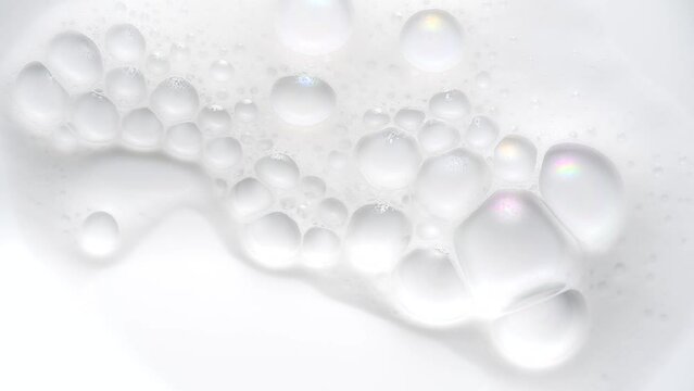 Foam bubbles background. Moving Soap foam popping bubble, white backdrop. Soap sud macro structure. Soap foam close-up. Clean, cleaning concept, laundry, shower. Slow motion. 