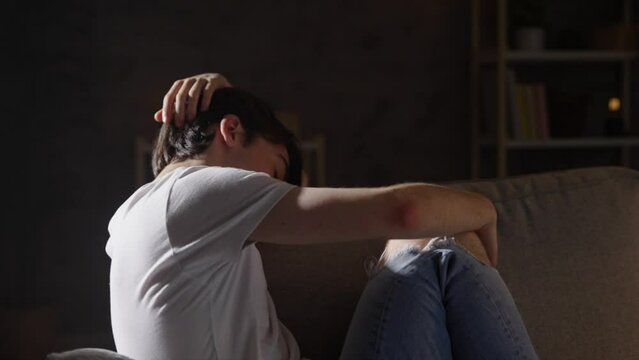 Sad teenager boy sitting on sofa. Depression, anxiety and loneliness concept.