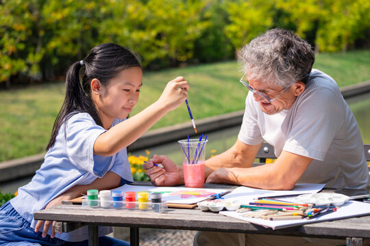 Naklejka teen girl enjoy painting with grandfather in the summer garden, concept family lifestyle,relationship,raising teen, the love of a family