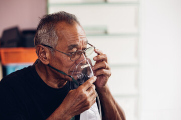 Elderly Senior Man wear oxygen inhaler device for helping breath respiratory. Patient use portable oxygen at home. Patients with respiratory disorders. portable oxygen concentrator or oxygen generator - obrazy, fototapety, plakaty