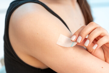 sticking a medical plaster on her shoulder