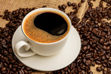 Black coffee or hot tea in a cappuccino espresso cup, breakfast food with coffee beans on a wooden table Isolated on a dark background, top view
