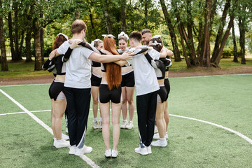 Cheerleader team standing together in circle outdoors and talking to each other
