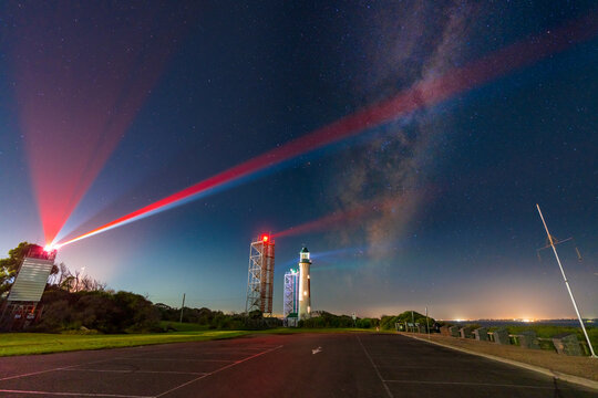 Night time scene of The Milky Way in a starry sky over a lighthouse and beacon towers