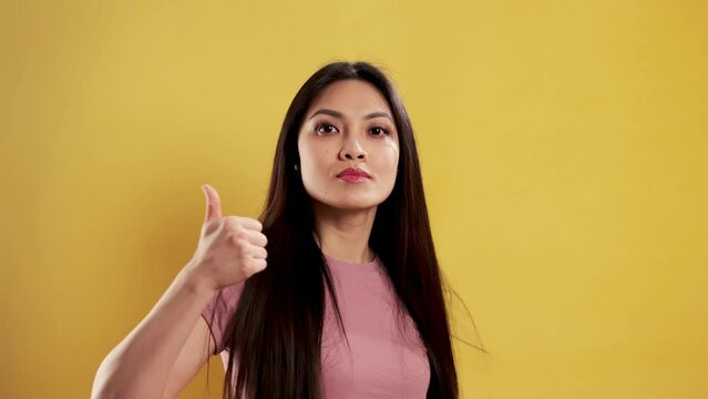 Asian Girl with a confident smile in a studio doing a thumbs-up gesture - extreme slow motion shot