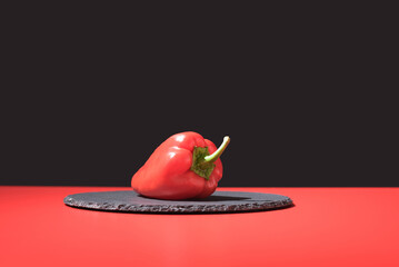 Pimiento rojo fresco sobre un plato de pizarra y fondo negro	