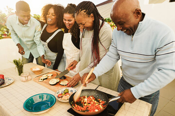Happy african family cooking outdoor at home rooftop terrace during summer time - Sunday dinner...