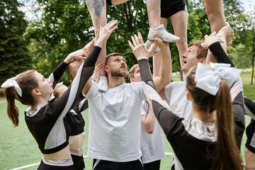 Cheerleader team training with coach outdoors before performance