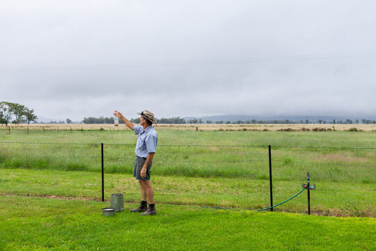 Farmer checking rain measurement on farm after rain storm has passed