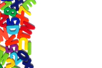 Many bright English letters of magnets lie on a white isolated background.	