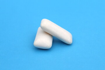 Two white chewing gum pads lie on a blue background.