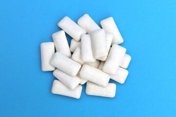 Fototapeta na wymiar Many white chewing gums lie on a blue background.