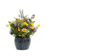 A bouquet of wild flowers of medicinal herbs stands in a vase on a white background.	