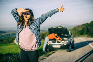 Young couples car broke down on the way. They hitchhike to find help. The hood is open and the...