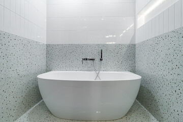 Large white modern bathtub for bathing and relaxing in the bathroom.