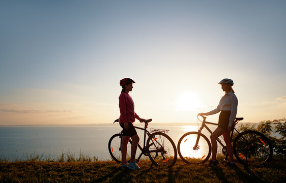 Two women with bicycles on the sea or lake shore