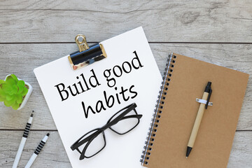 a4 paper. glasses on a white page on a working table. text Build good habits symbol.