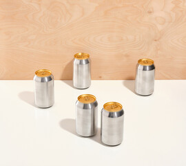 Aluminum metal cans of refreshments and other drinks stand in various places on a white table. Mirror reflection.