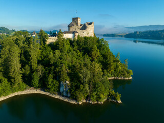 Naklejka premium Poland. Medieval Castle in Niedzica, 14th century (upper castle), Polish or Hungarian in the Past. Artificial Czorsztyn Lake. Far view of the ruin of Czorsztyn castle, Aerial view in sunrise light