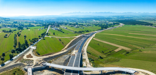 New fragment of highway under construction on Zakopianka road in Poland, from Krakow to Zakopane clearing Nowy Targ town, main place of traffic jams. State in July 2023. Tatra mountains in background - 625180931