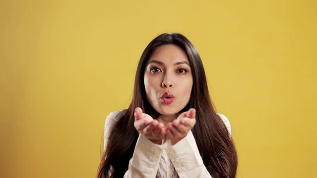 Asian Girl with a confident smile in a studio sending a kiss to the camera - extreme slow motion shot